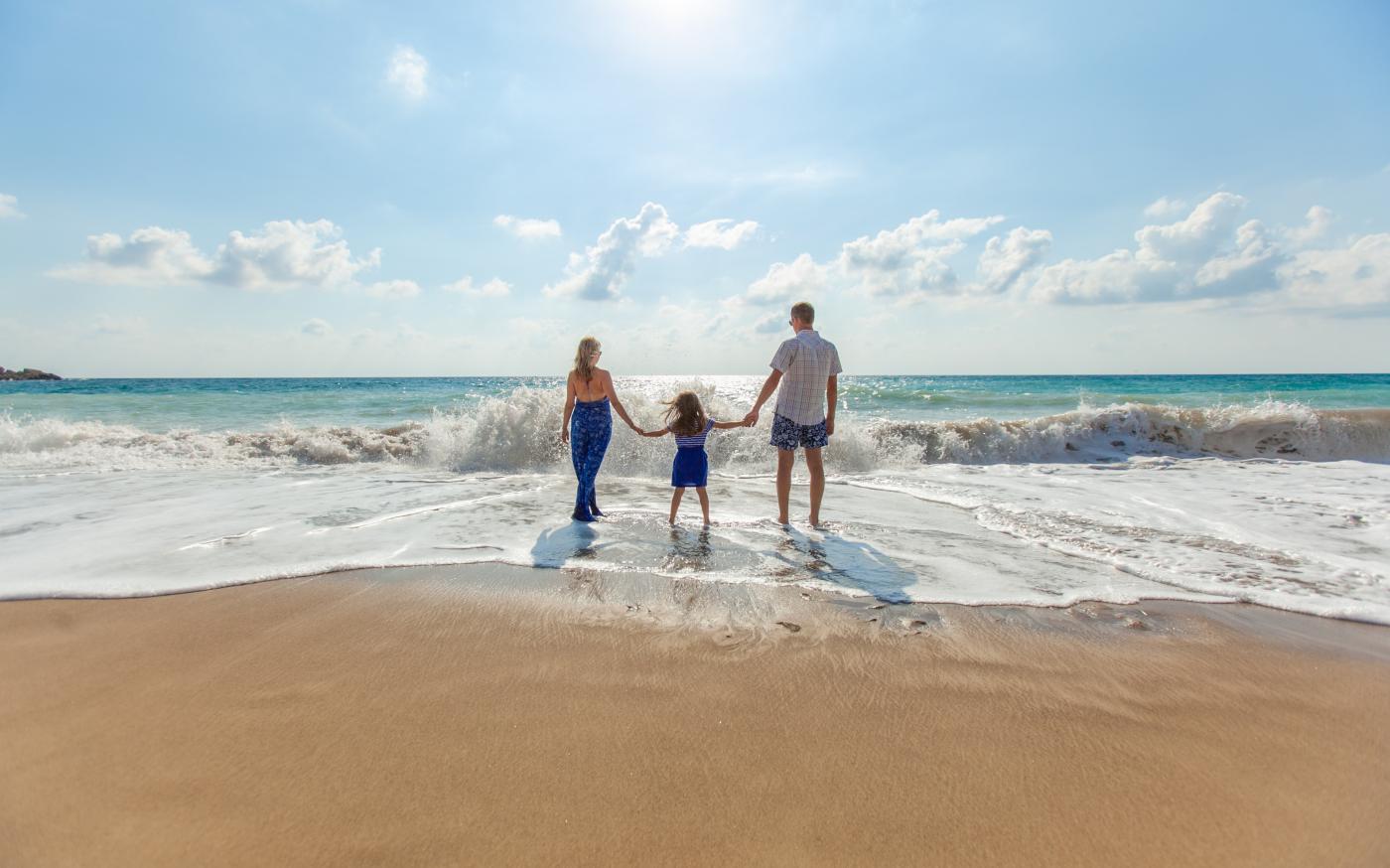 man, woman and child holding hands on seashore by Natalya Zaritskaya courtesy of Unsplash.