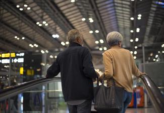 Elderly couple going up escalator at an airport terminal