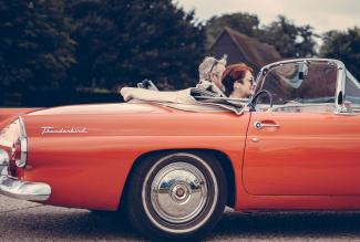 two people riding in a vintage thunderbird convertible with top down
