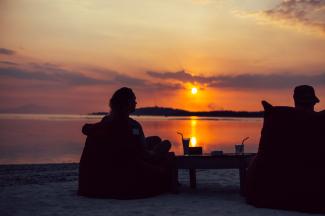 silhouette of couple sitting on chairs on beach during sunset by Kaur Martin courtesy of Unsplash.