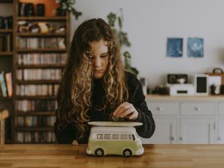 girl putting a money into a car shaped piggy bank