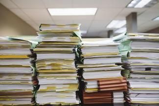 stack of books and files on table by Wesley Tingey courtesy of Unsplash.