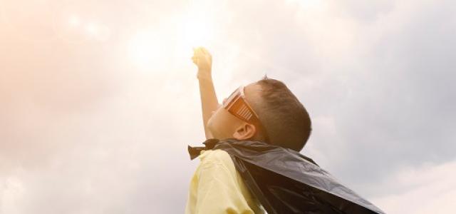 child dressed in a cape looking up towards sky