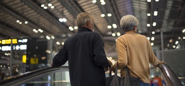 Elderly couple going up escalator at an airport terminal