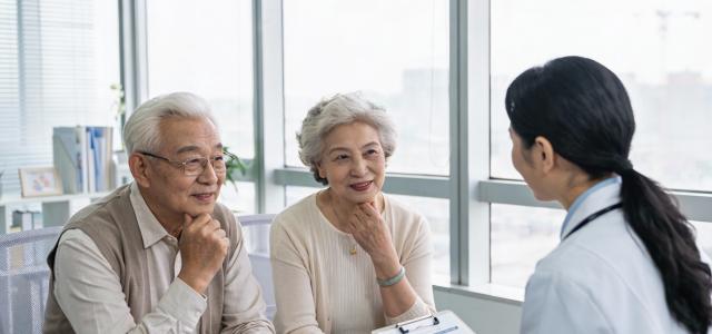Retired couple discussing Medicare and Medicaid options with a medical professional in a clinic near Marlton, NJ. 