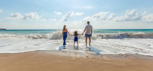 man, woman and child holding hands on seashore by Natalya Zaritskaya courtesy of Unsplash.