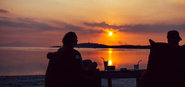 silhouette of couple sitting on chairs on beach during sunset by Kaur Martin courtesy of Unsplash.