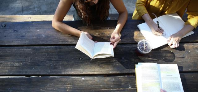 3 older students at picnic table with open books